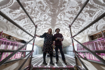 Two visitors standing on scaffolding to view the Long Gallery ceiling at National Trust Lanhydrock, Cornwall. Conservation experts are working onsite to repair and restore the 400 year old work of art. Copyright: National Trust Images / Steve Haywood.