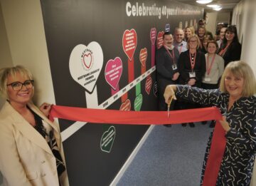 The big reveal: CEO Sarah Hicks with Mary Nesbitt with members of staff behind. Image: Sharon Goble.